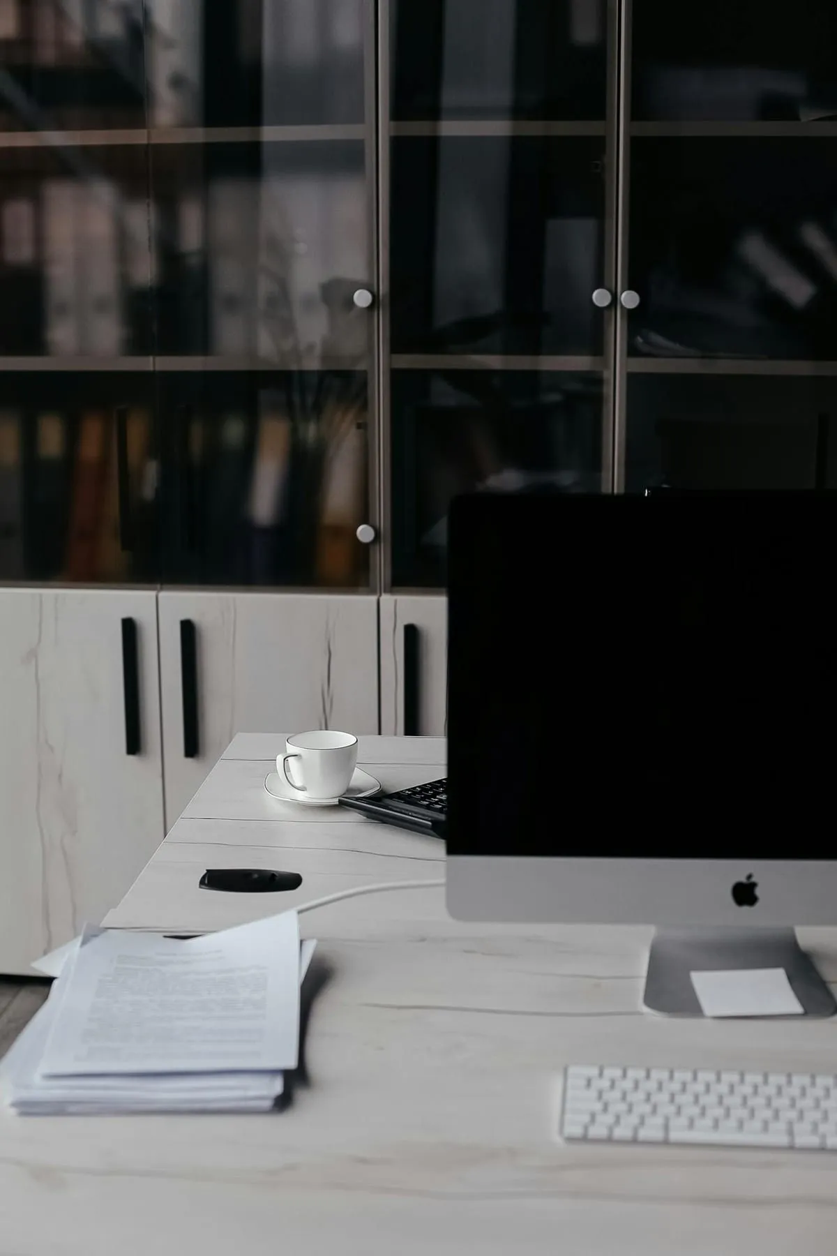 A clean desk with a stack of documents and a keyboard on a marble surface
