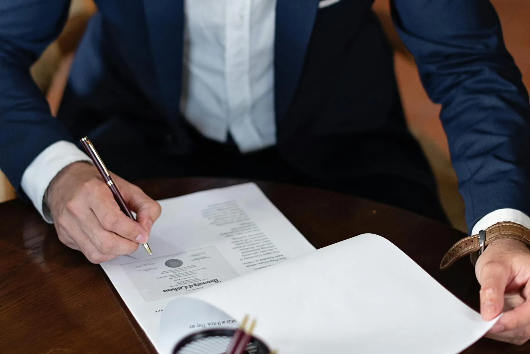 A hand signing a formal document with a fountain pen